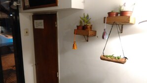 A hallway with a wooden door, a small shelf with potted plants, and a hanging plant. - My home in Buenos Aires | 1937 sqft | 2 bdr | n/STelmo (Barracas)
