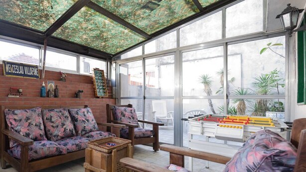 A sunroom with a wooden bench, a sofa, and a table with a foosball table. - My home in Buenos Aires | 1937 sqft | 2 bdr | n/STelmo (Barracas)