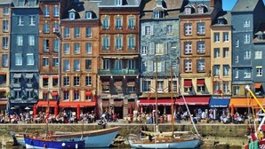 A waterfront with historic buildings, a dock with boats, and a crowd of people. - La Maison des Arts (Honfleur)