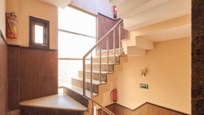 Una escalera con barandilla de metal, peldaños de madera y un letrero de salida.