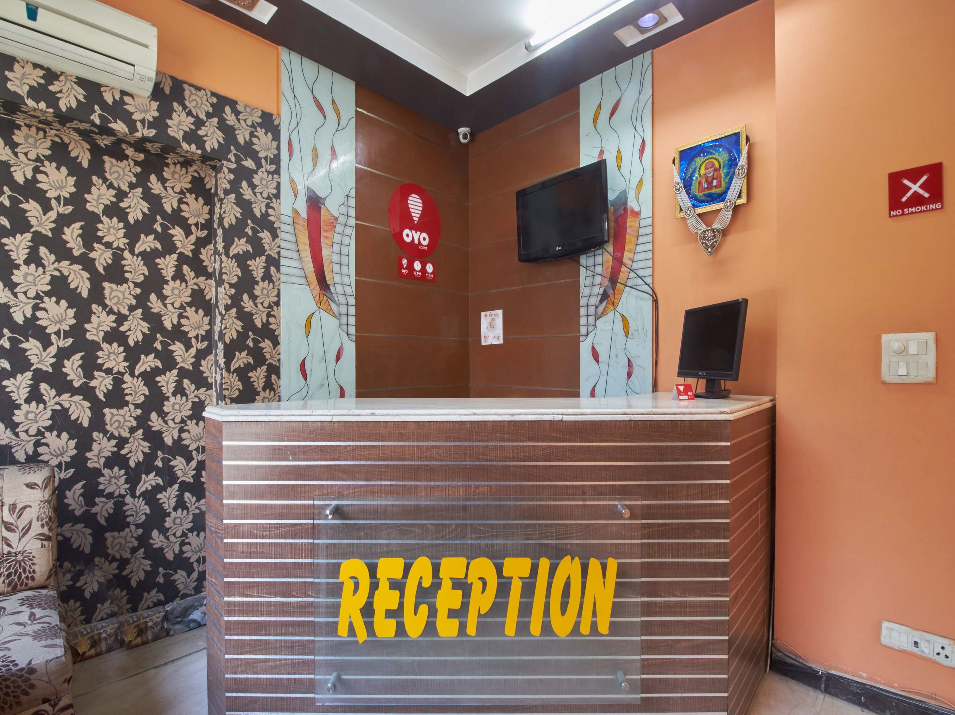 Een receptiegedeelte met een bord waarop 'RECEPTION' staat, een bord met 'ROOKVRIJ' en een televisie die aan de muur is bevestigd.