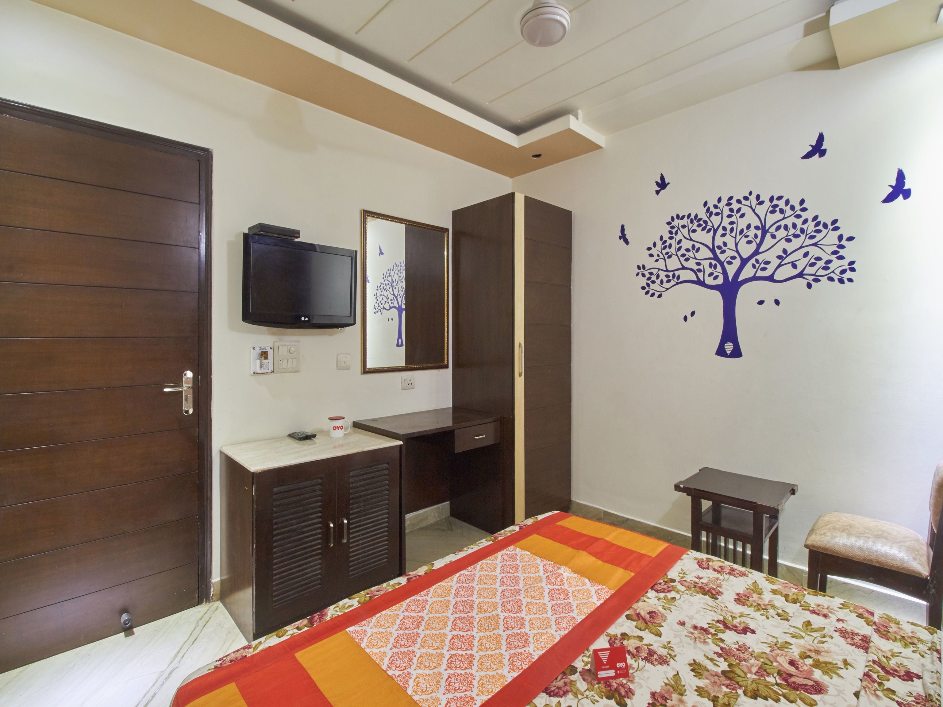 Un dormitorio con cama, escritorio, silla, televisor y armario.
