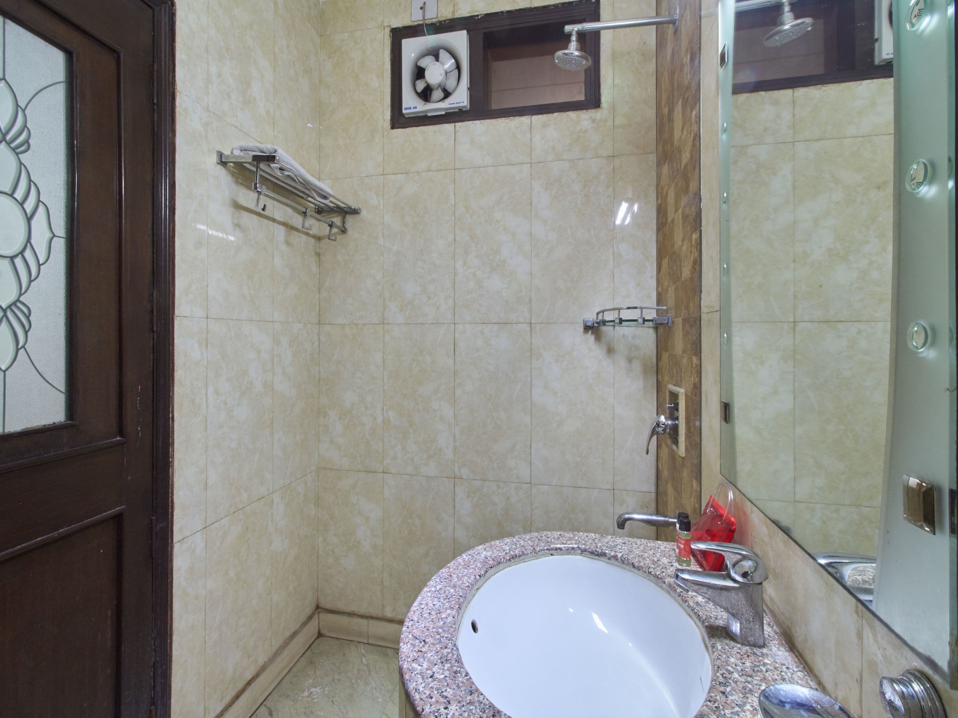 Een badkamer met een wastafel, spiegel, douche en handdoekhouder.
