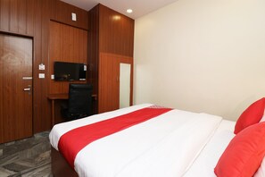 A hotel room with a bed, a desk, a television, and wooden paneling. - OYO Flagship 23709 Hotel Meerut International (Meerut)