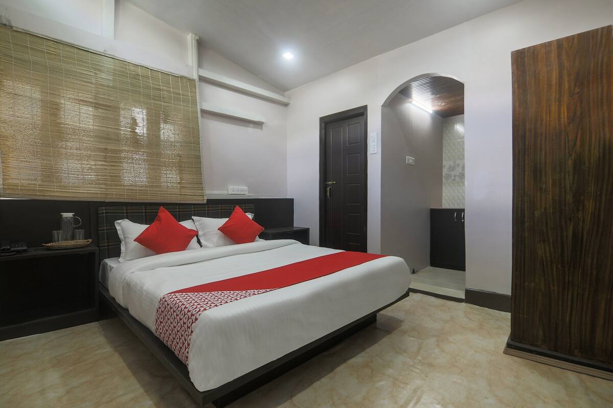 A neatly arranged hotel room with a bed, bedside tables, a wardrobe, and a mirror.