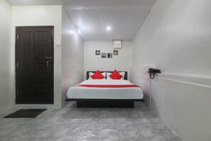 A bedroom with a bed, a door, a wall-mounted shelf, and a small rug. - OYO 19292 55 Pillars House (Shillong)