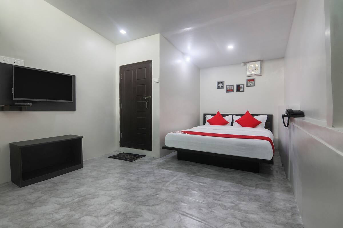 A bedroom with a bed, a TV mounted on the wall, and a door.