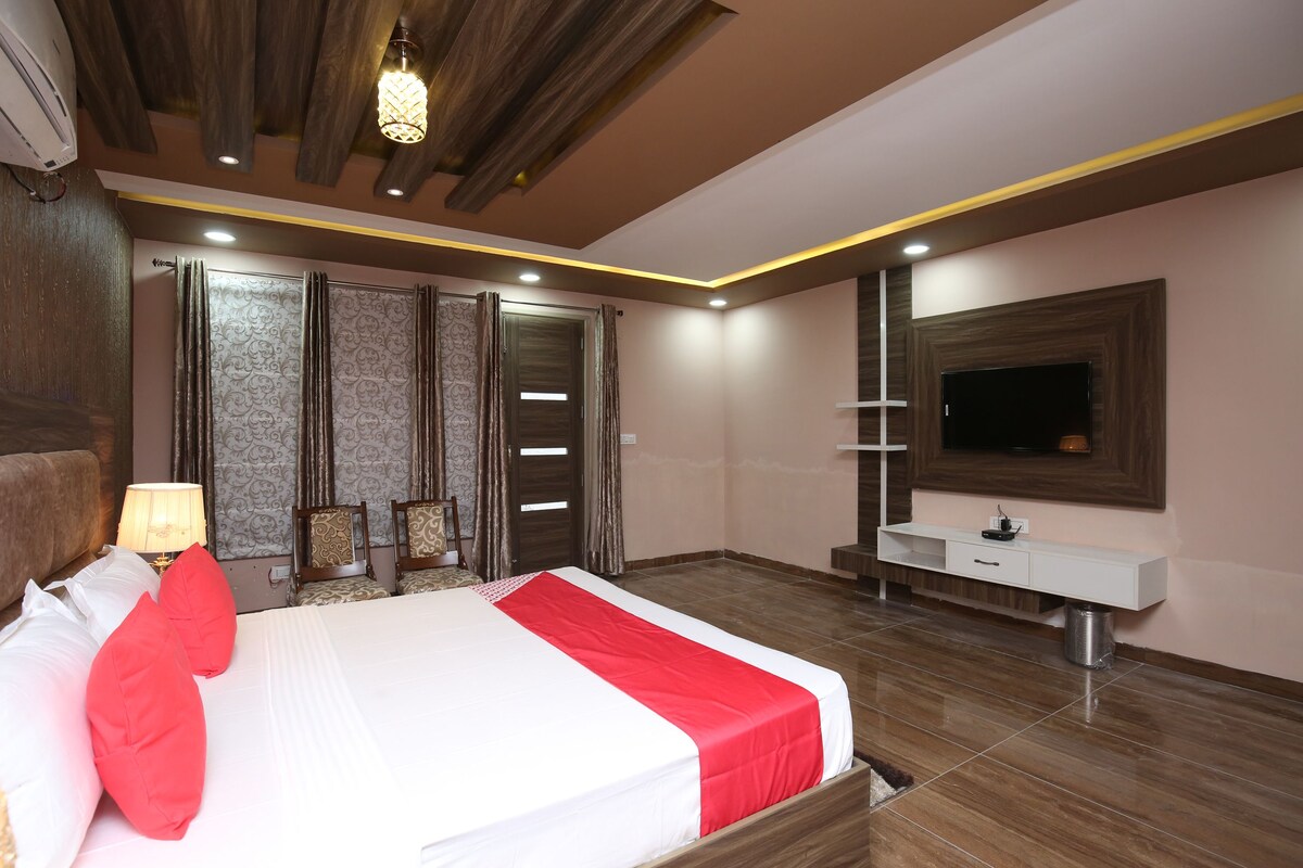A modern bedroom with a large bed, a TV mounted on the wall, and a bedside table.