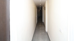 A narrow hallway with white walls and a grey floor, leading to a staircase.