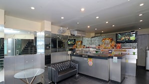 A modern hotel lobby with a reception desk, a seating area, and a television.