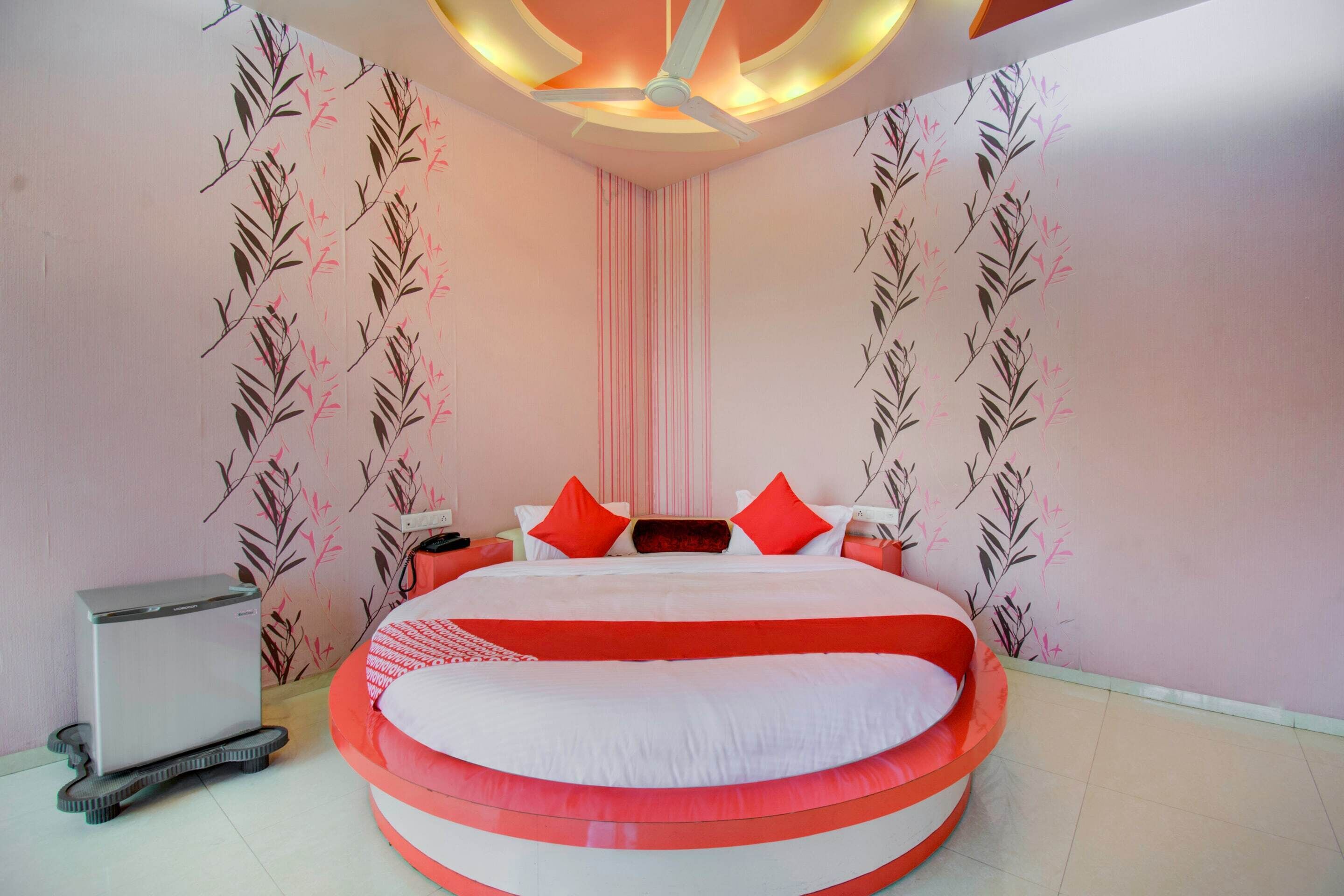 A modern bedroom with a circular bed, a ceiling fan, and a small heater.