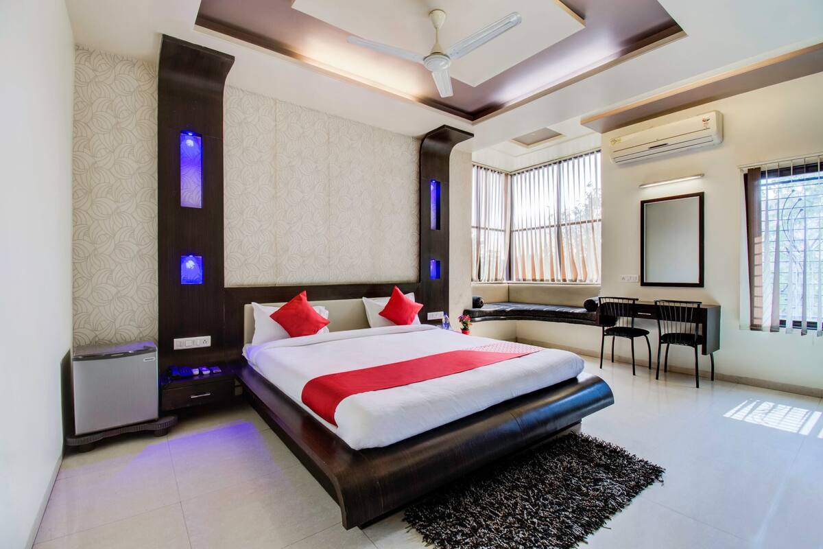 Una habitación de hotel moderna con una cama grande, un escritorio, una silla y un refrigerador pequeño.