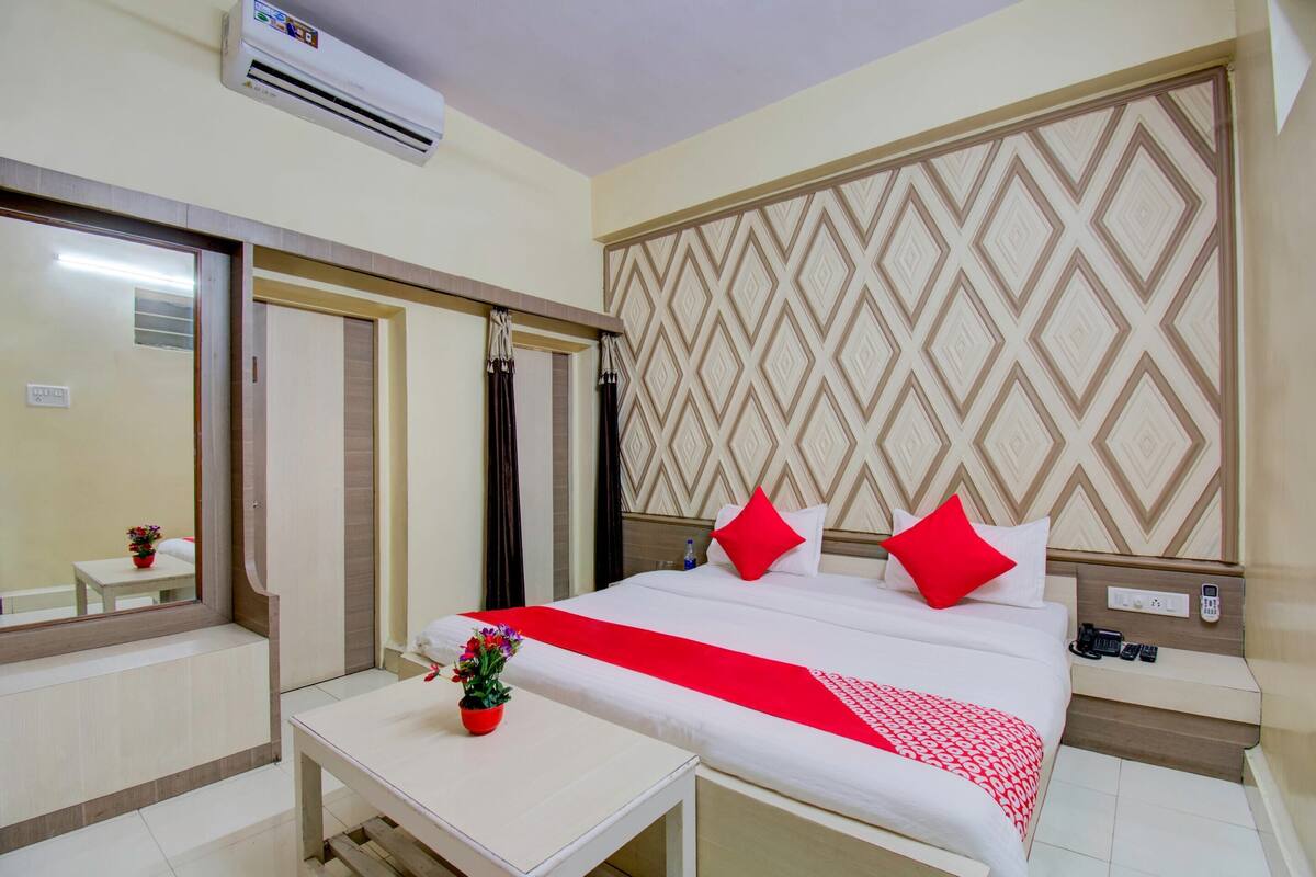 Una habitación de hotel con cama, mesita de noche y una pequeña mesa con una planta.