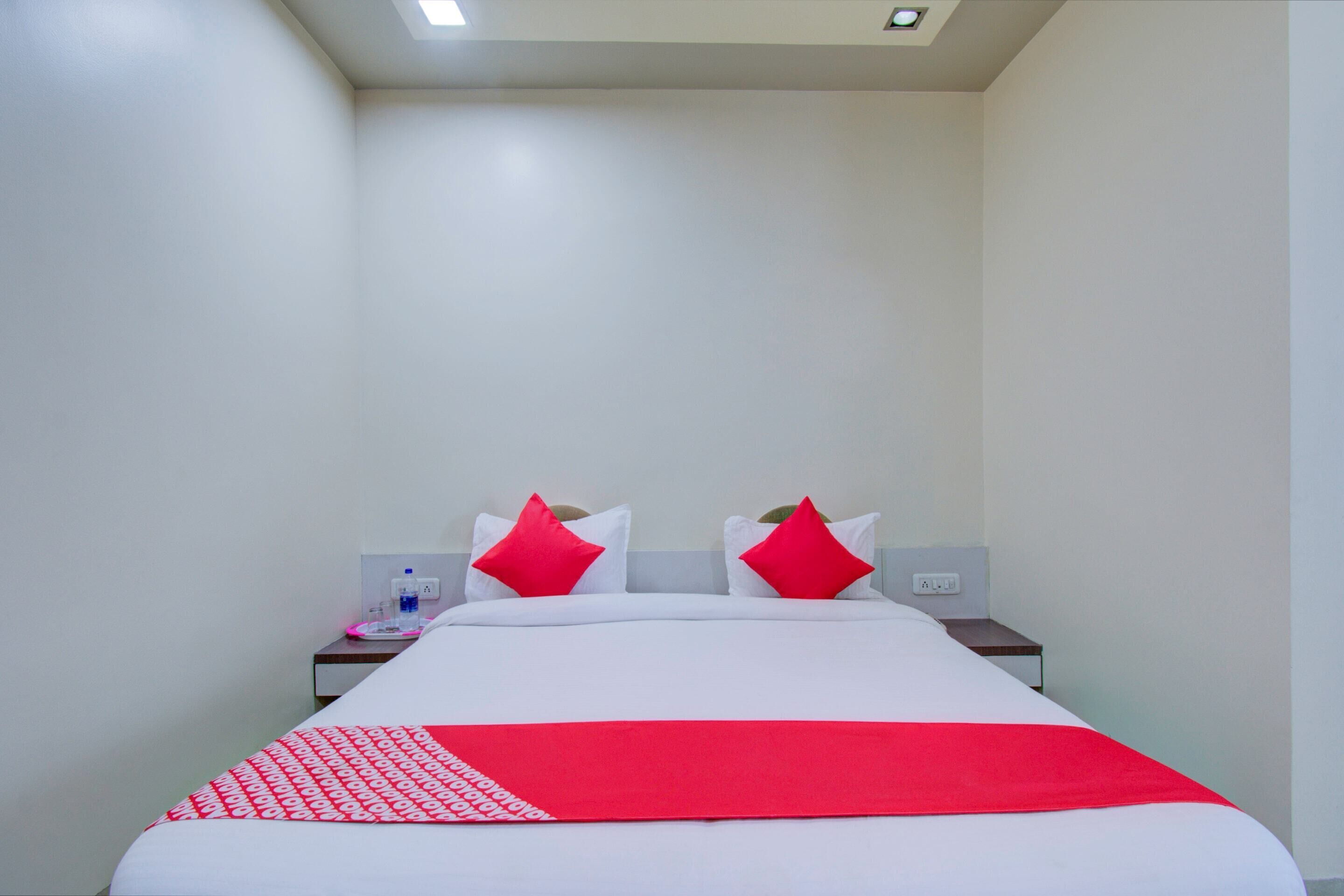 Ein Hotelzimmer mit einem großen Bett, zwei roten Kissen, einer weißen Bettdecke und einer roten Decke.