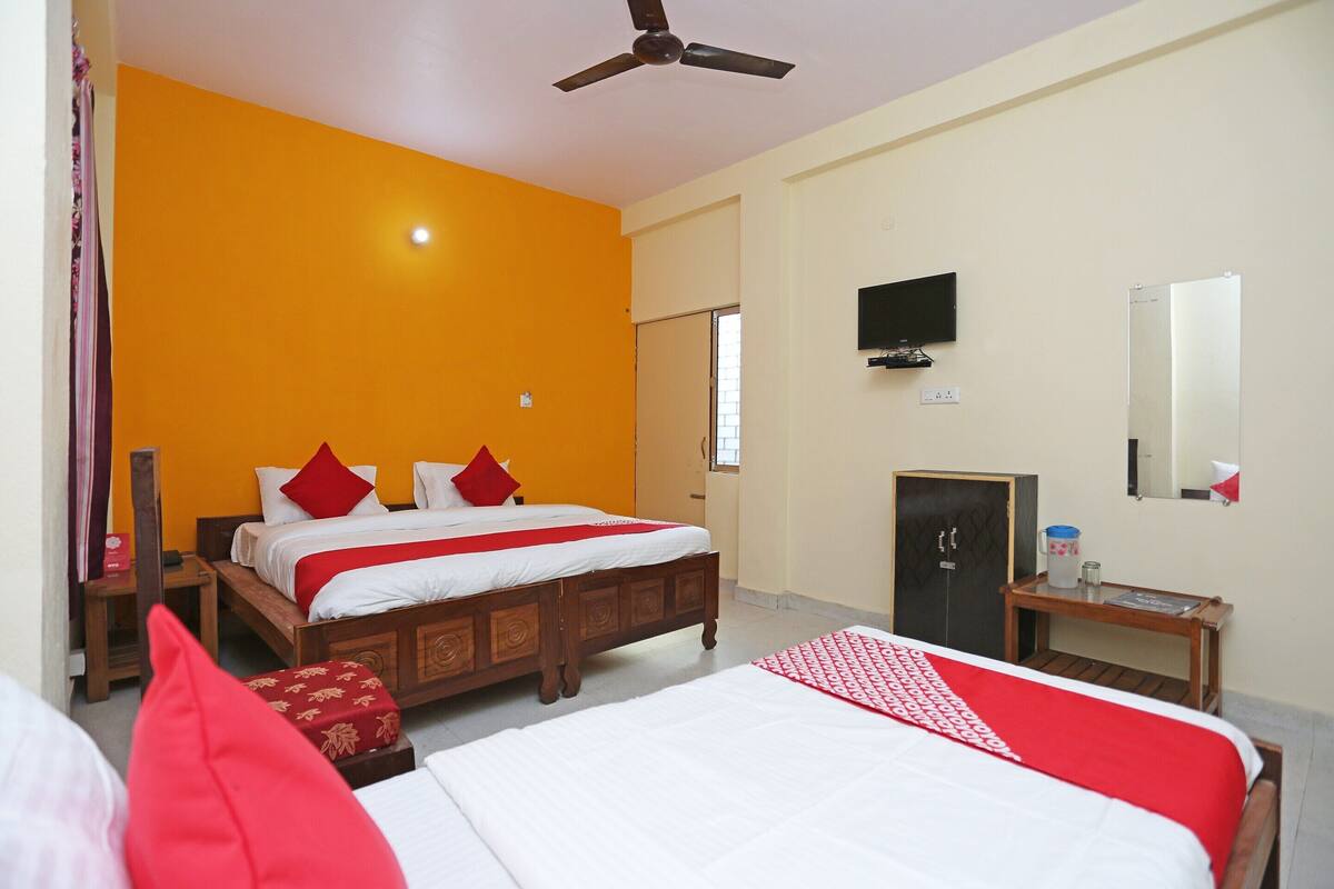 A hotel room with a large bed, a ceiling fan, a TV, and a wardrobe.
