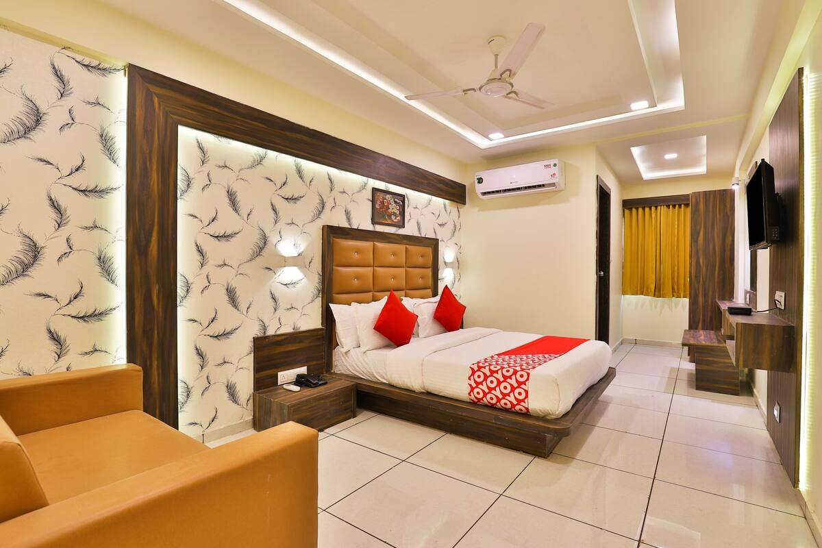 A hotel room with a bed, a sofa, a TV, and a ceiling fan.