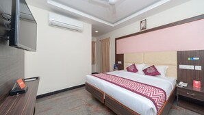 A hotel room with a bed, a desk, a TV, an air conditioner, and a ceiling fan. - OYO 16595 Famous Residency (Tiruchirappalli)