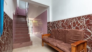 Un interior moderno con un banco de madera, una escalera y una pared de mármol.