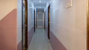 Un pasillo con piso de baldosas, puertas a ambos lados e iluminación empotrada en el techo.