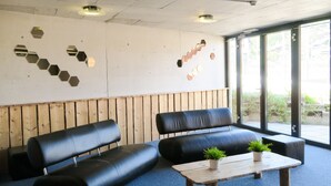 A modern waiting area with black leather sofas, a wooden coffee table, and hexagonal wall decorations. - Hotel le Palladium (Champery)