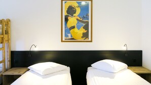 A room with two single beds, wooden headboards, and a framed poster on the wall. - Hotel le Palladium (Champery)