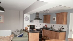 Une cuisine compacte comprenant un coin repas, un four à micro-ondes, une cuisinière et des placards en bois.