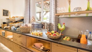 A breakfast buffet with various food items, a decorative rooster, and a juice dispenser.