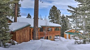 A wooden cabin with a balcony, surrounded by snow-covered trees and a clear sky. - Bright & Cozy Duck Creek Cabin w/ Grill & Fire Pit (Duck Creek Village)