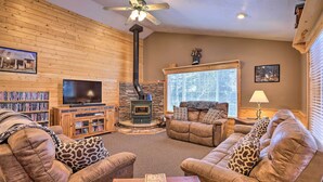 A cozy living room with a fireplace, leather sofas, a television, and a bookshelf. - Bright & Cozy Duck Creek Cabin w/ Grill & Fire Pit (Duck Creek Village)