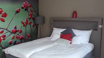 A modern bedroom with a bed, a headboard, a wall-mounted light, and a red decorative item.