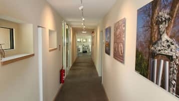 A hallway with a fire extinguisher, a fire alarm, and artwork on the walls.