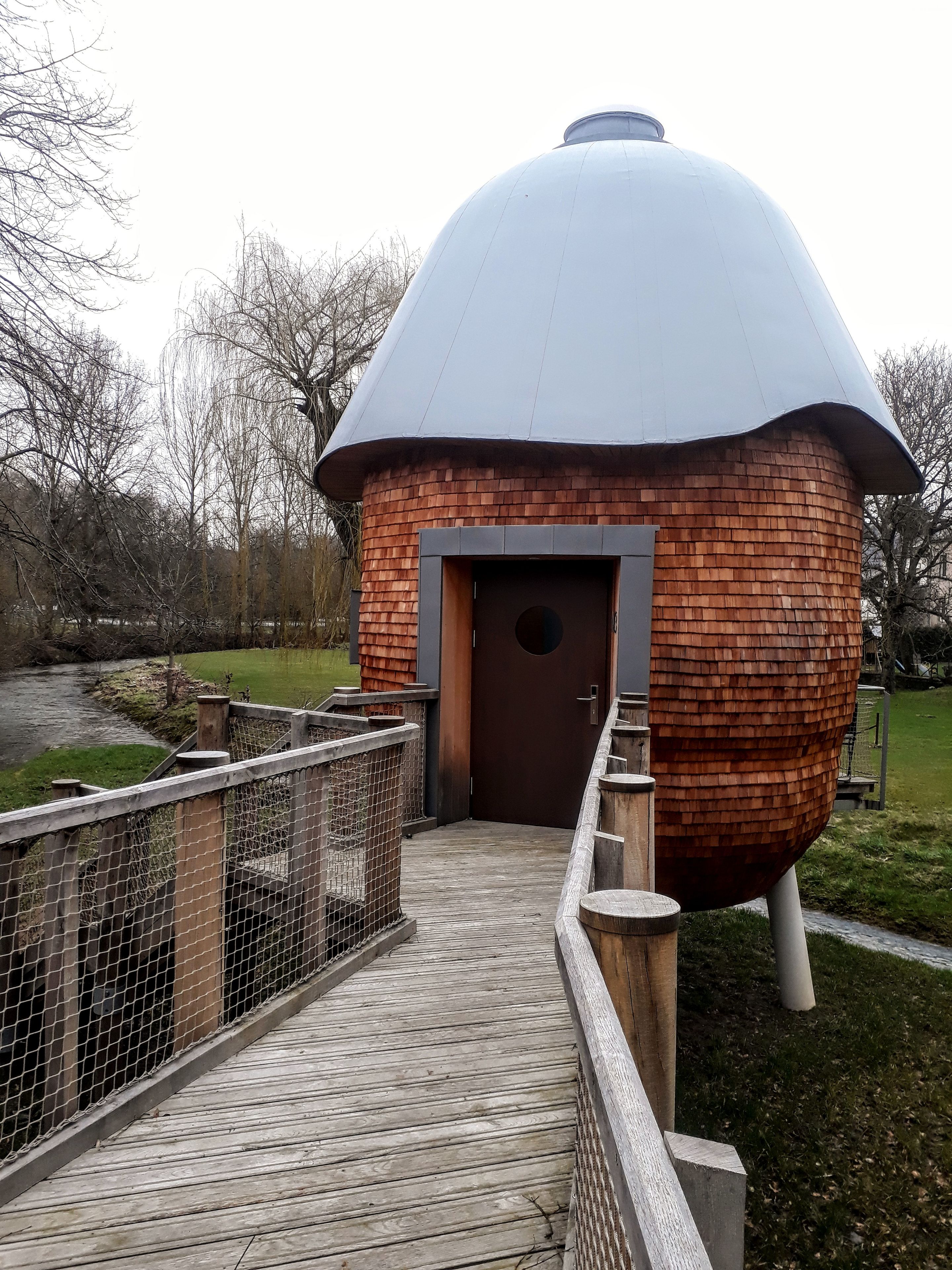 A wooden dome structure with a door and a wooden walkway leading to it.