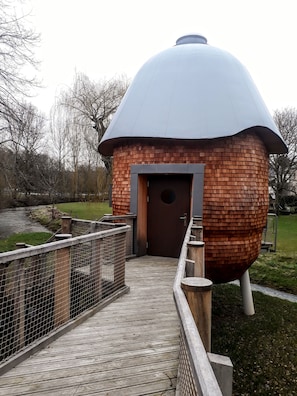 Una estructura en forma de cúpula de madera con una puerta y un pasillo de madera que la conduce.