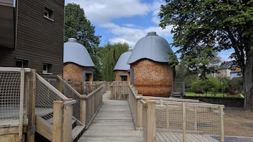 Un sendero de madera que conduce a una hilera de edificios con forma de cúpula y base de ladrillo.