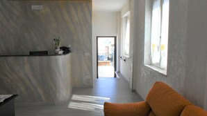 Ein Korridor mit Marmorwand, einer Rezeption, einer Pflanze und einem Fenster mit Vorhängen.