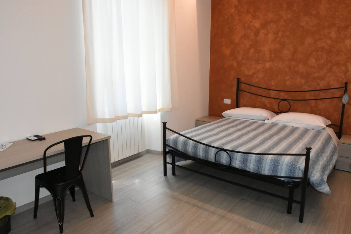 A bedroom with a bed, a desk, and a chair.