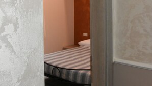 Ein Zimmer mit einem Bett, einer Holztür und einer kleinen Wandleuchte.