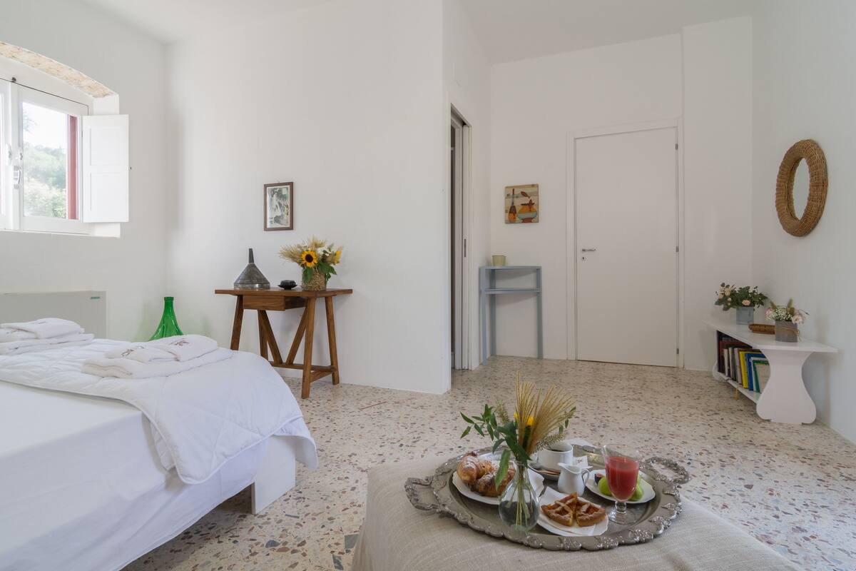 Une chambre à coucher avec un lit, une petite table sur laquelle se trouve un plateau de nourriture, une fenêtre et une porte.