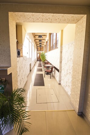 A hallway with patterned walls, a wooden table with chairs, and potted plants.