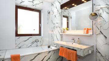 Ein Badezimmer mit Marmorwand, integriertem Waschbecken, Spiegel, Fenster und Dusche.