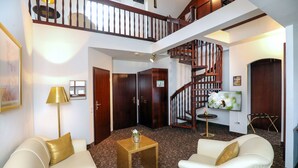 A spacious living area with a high ceiling, a staircase, and a flat-screen TV mounted on the wall. - City-Hotel Aschaffenburg (Aschaffenburg)