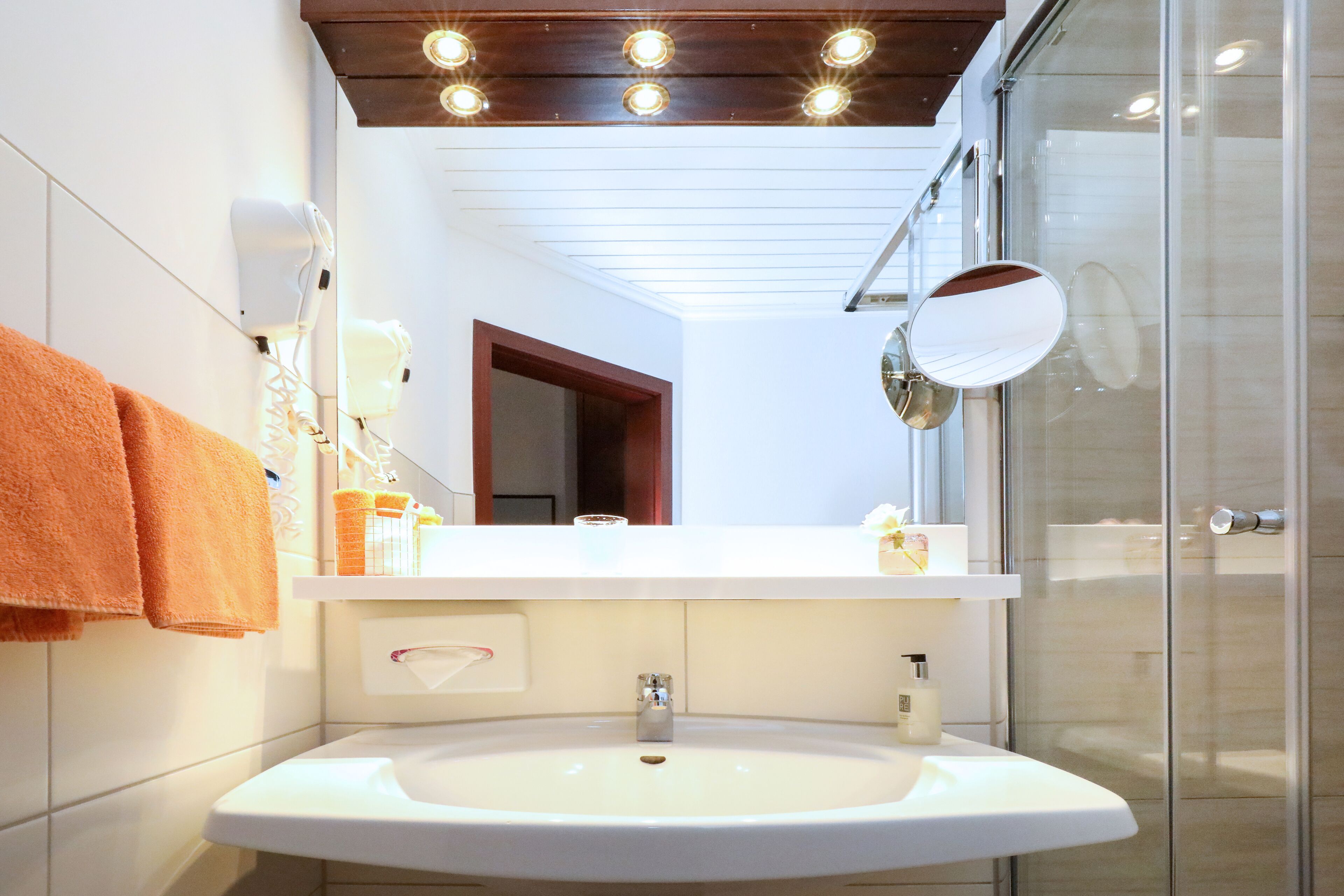 A modern bathroom with a white sink, a mirror, and a glass shower enclosure.