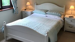A white bed with a quilted cover, two bedside tables with lamps, and a window with curtains. - Claddagh Guest House (Oxford)