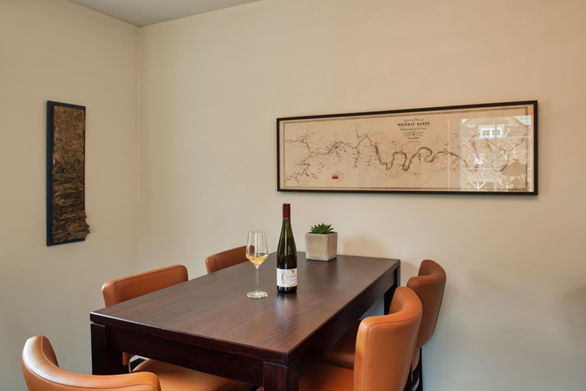 A dining area with a wooden table, four chairs, a wine bottle, and a glass.