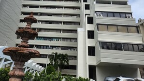 A multi-story building with a modern design, featuring a series of balconies and air conditioning units.