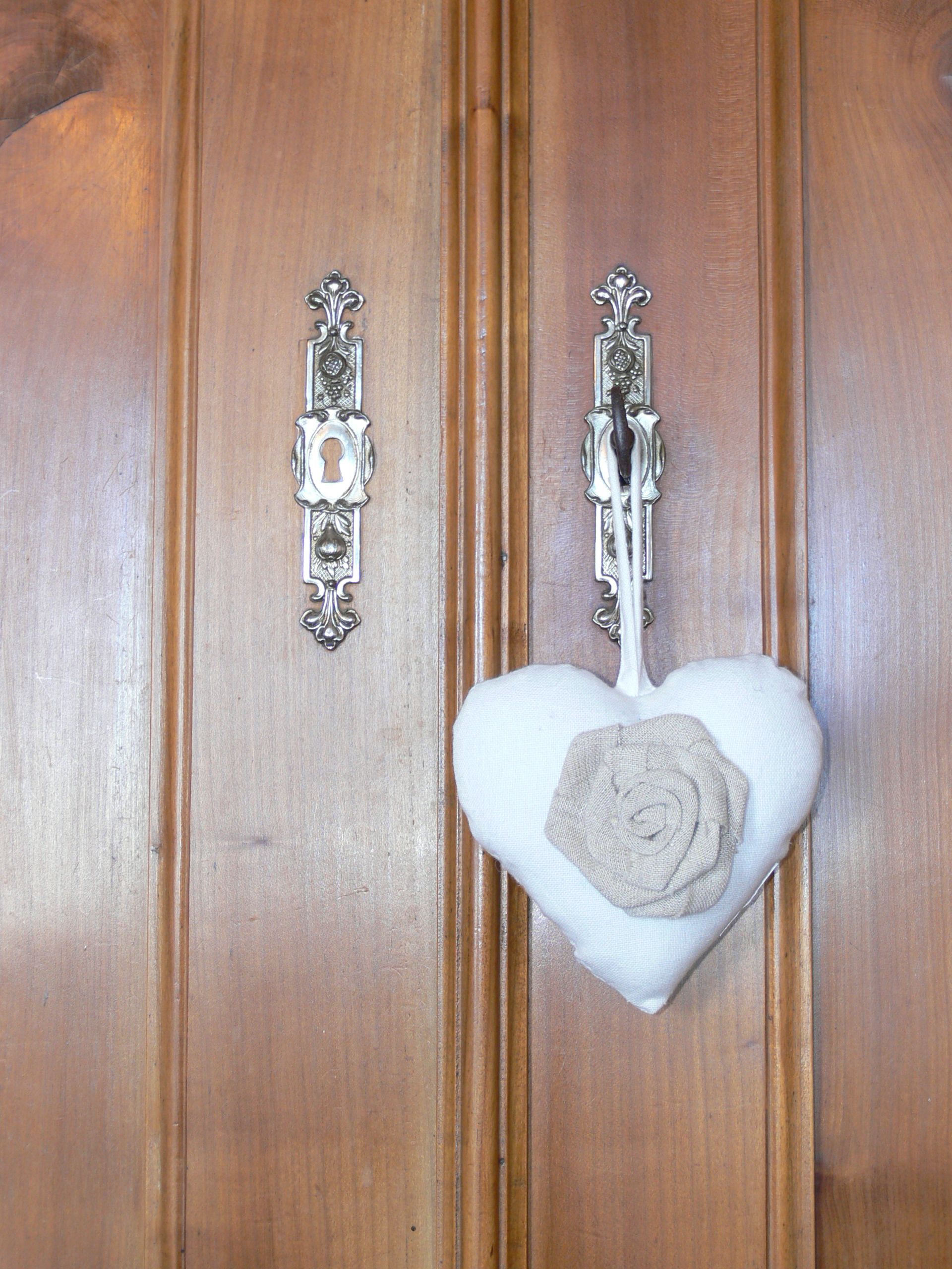 Una puerta de madera con dos pomos de metal y una decoración con forma de corazón.