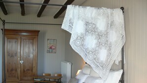 Un dormitorio con una cama con dosel, un armario de madera, una mesa y una silla.