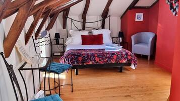 Een slaapkamer met een bed, een stoel, een bureau en een rode muur.