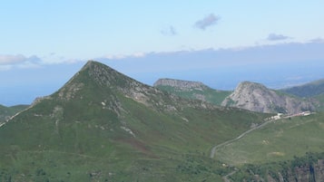 Paisaje montañoso con una carretera sinuosa y un edificio de techo rojo.