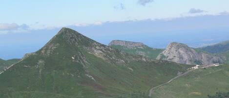 A mountainous landscape with a winding road and a building with a red roof.